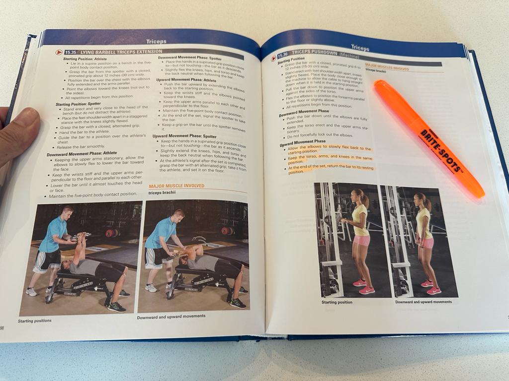 An open textbook showing pages of the NSCA CSCS with form and technique being shown