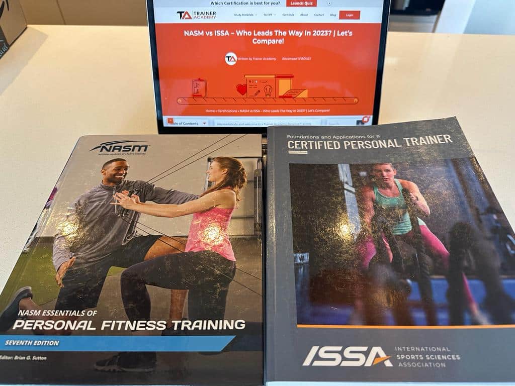 NASM personal training textbook and ISSA personal training textbook sitting on a laptop open to a page for the comparison article